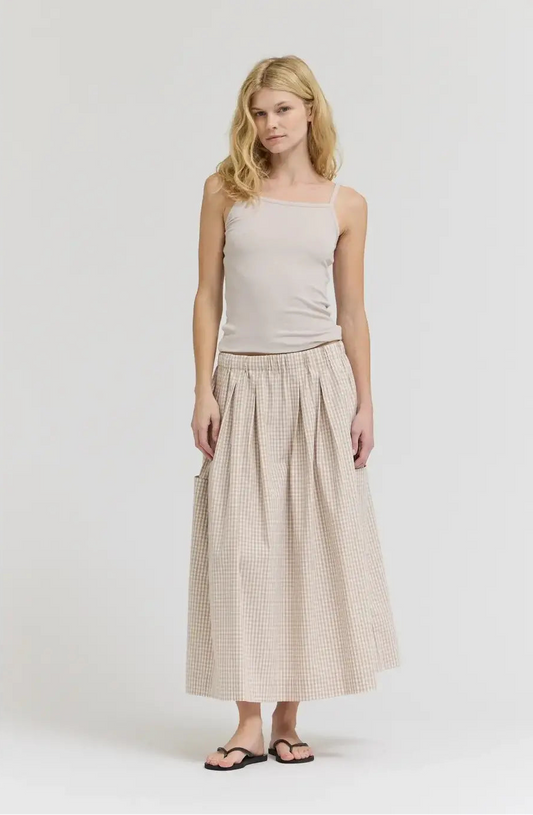 Woman wearing a beige sleeveless top and checkered skirt on a white background